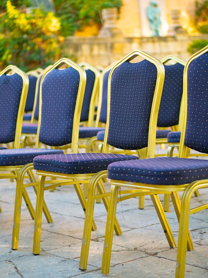 Rows of elegant blue and gold chairs arranged in an outdoor venue for an event.