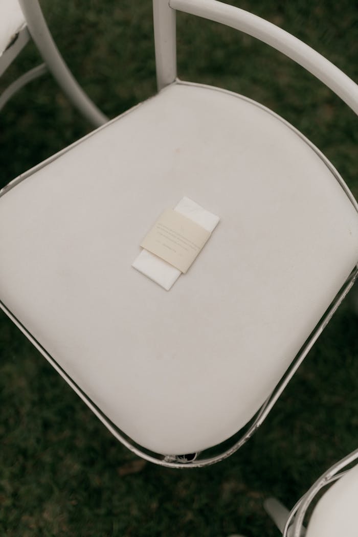 Elegant white chair with place card set on a green lawn, perfect for outdoor events